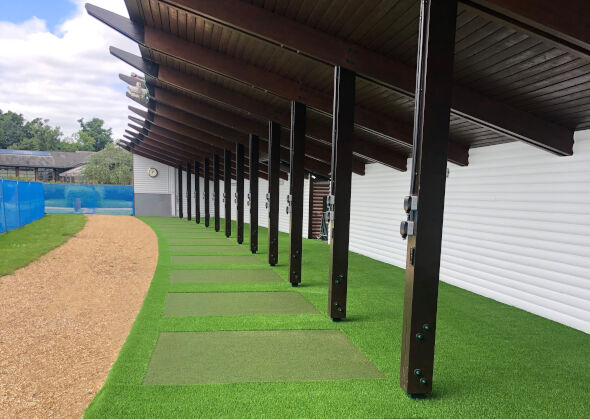 Flagstaff Covered outdoor tee line with light green synthetic grass boxes inside a dark green synthetic grass strip